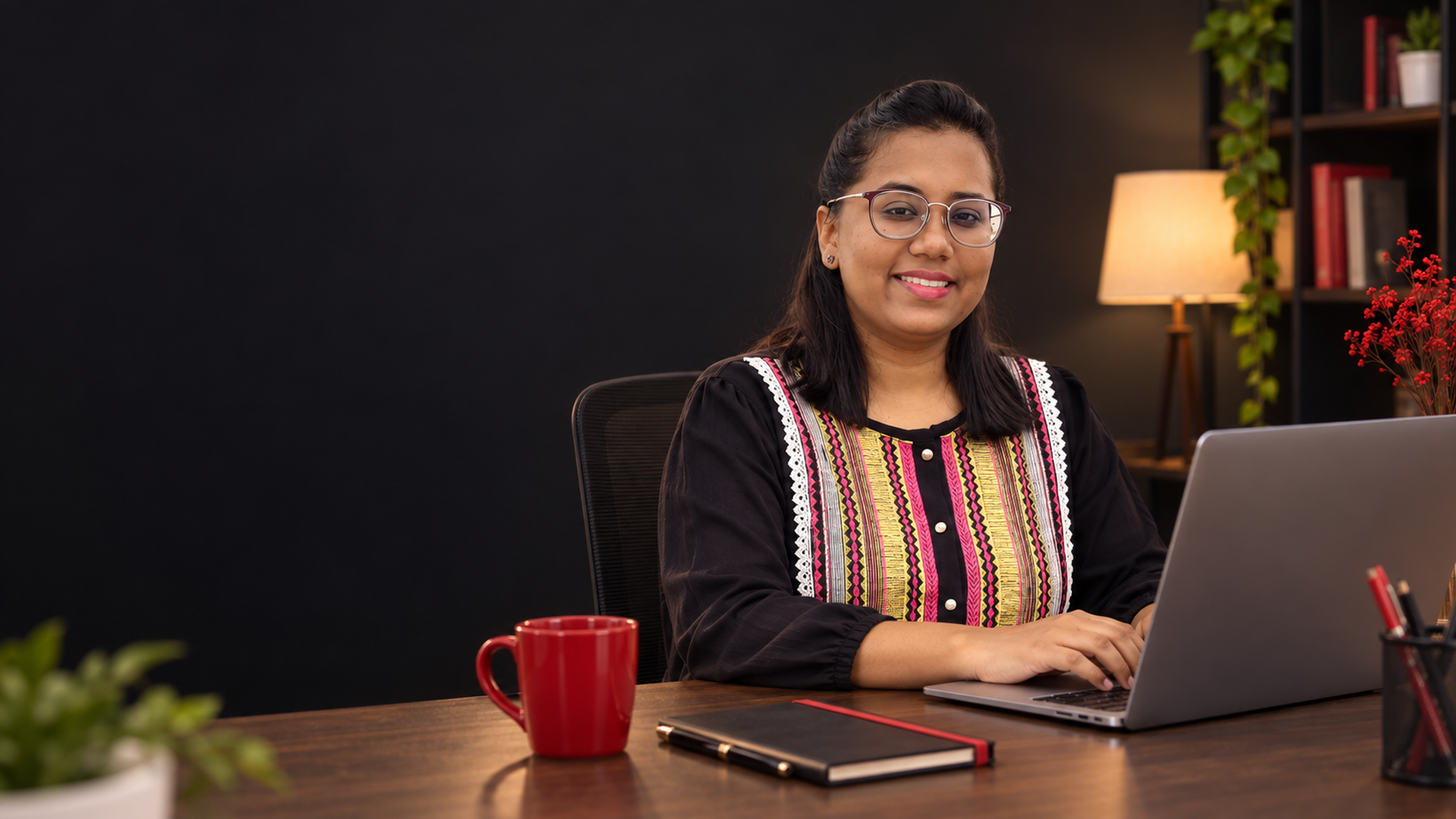 Sabrina seated at her desk working on a laptop